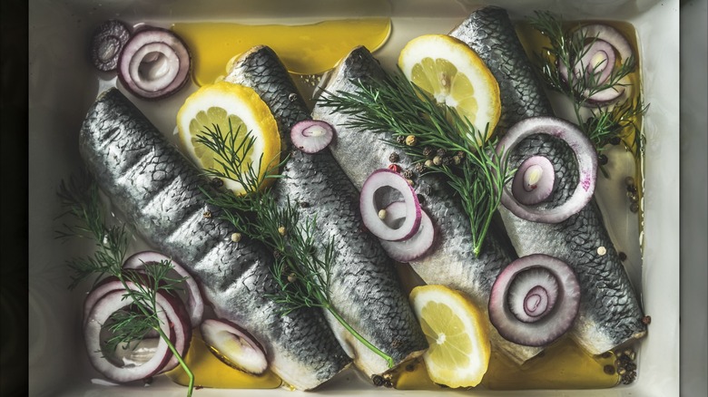 Pickled herring with onion, oil, and lemon on plate