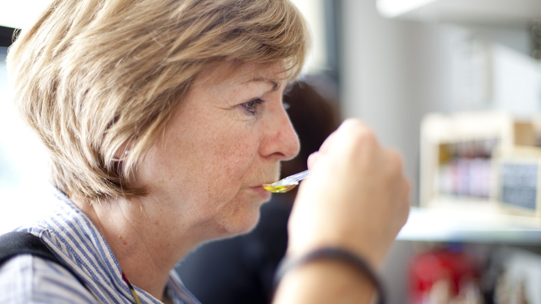 Woman tasting olive oil on spoon