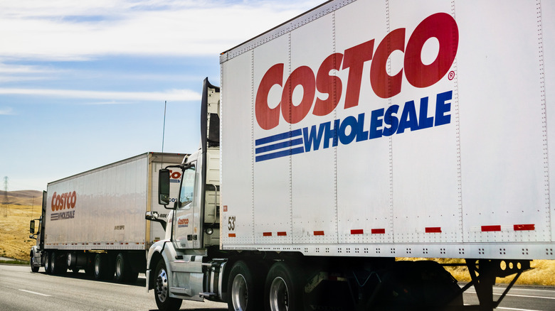Two Costco trucks driving on an interstate.