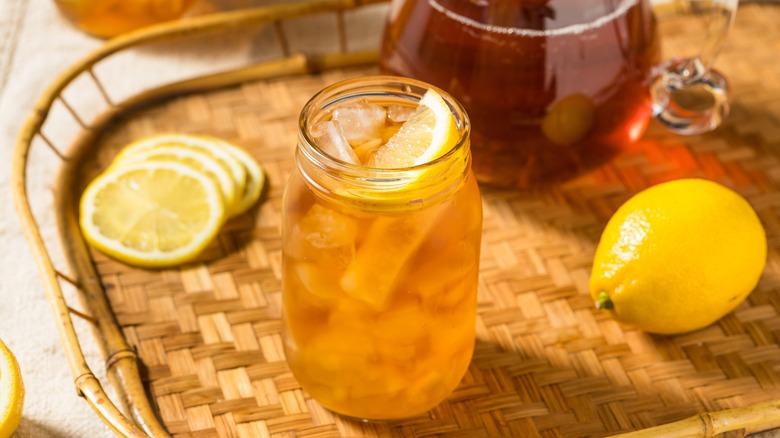 Close up of the top of a glass of iced tea with lemon on it.