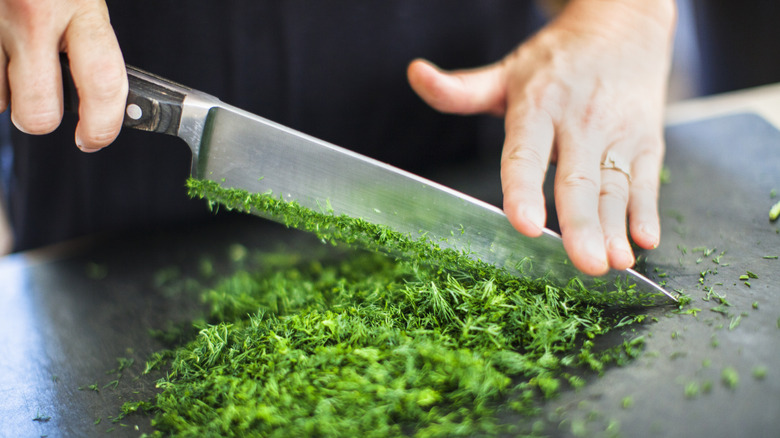 hands cutting herbs with large knife