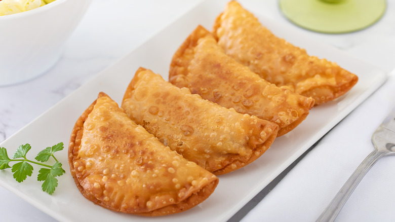 Four empanadillas on a white plate.