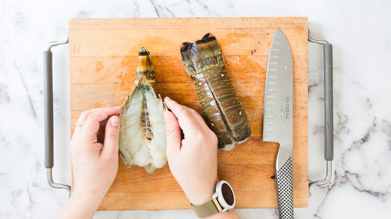 Hands opening cut lobster tail