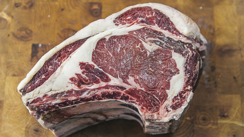 Uncooked prime rib cut on wooden surface