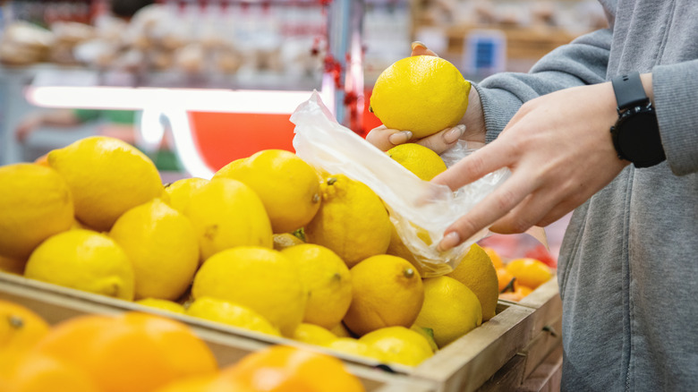 Person putting lemons in bag at grocery store