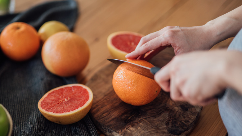 Person cutting a grapefruit with a knife