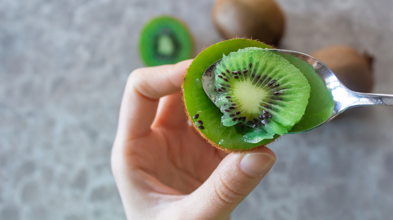 Person scooping kiwi flesh with a spoon