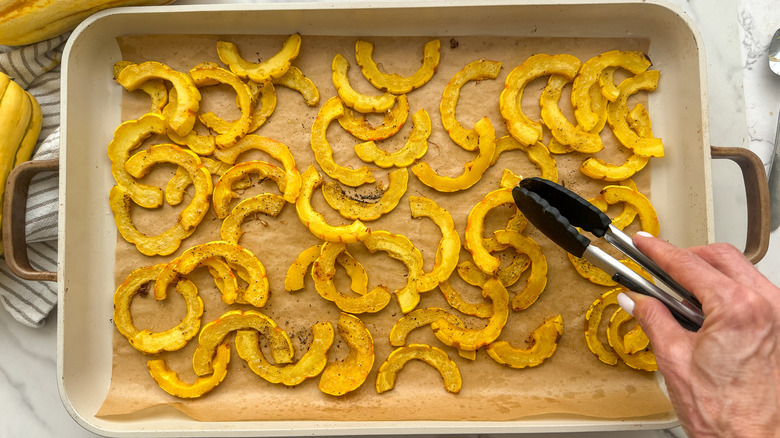 hand using tongs on squash