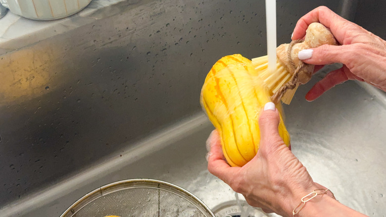 hands scrubbing squash in sink