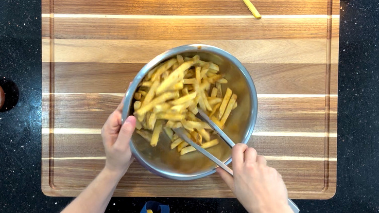 Tossing french fries with tongs