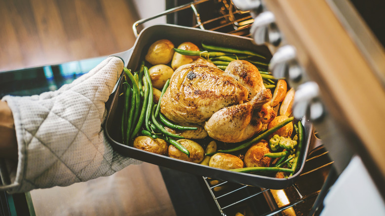 Taking roasted chicken and veggies out of the oven