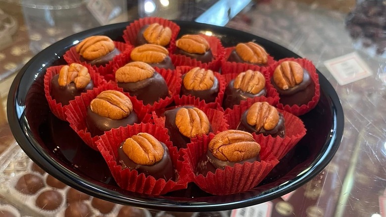 Bourbon balls with nuts on top on a black plate