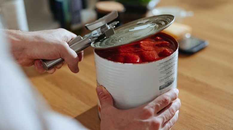 Hands opening can with can opener