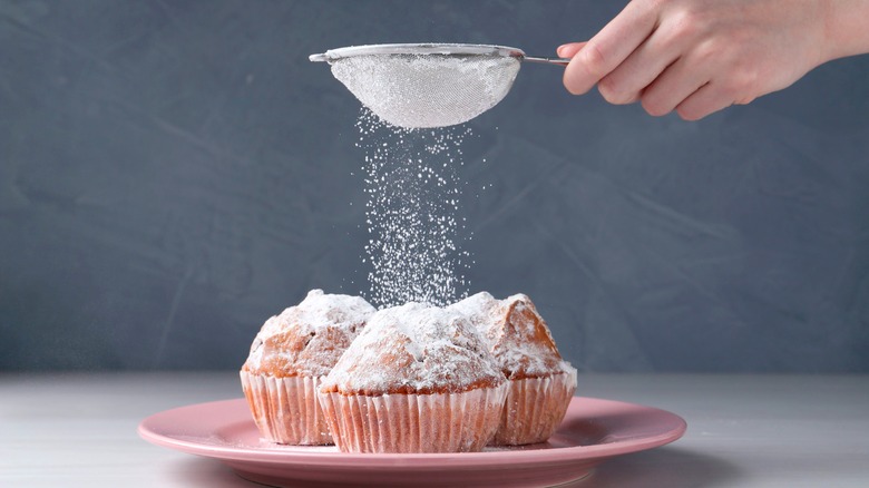 Sifting powdered sugar on muffins