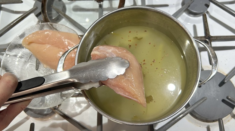 chicken breast in tongs with broth