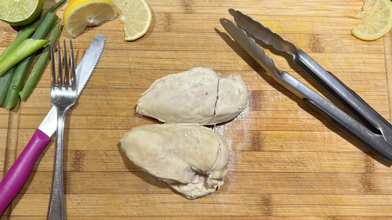 two poached chicken breasts cutting board