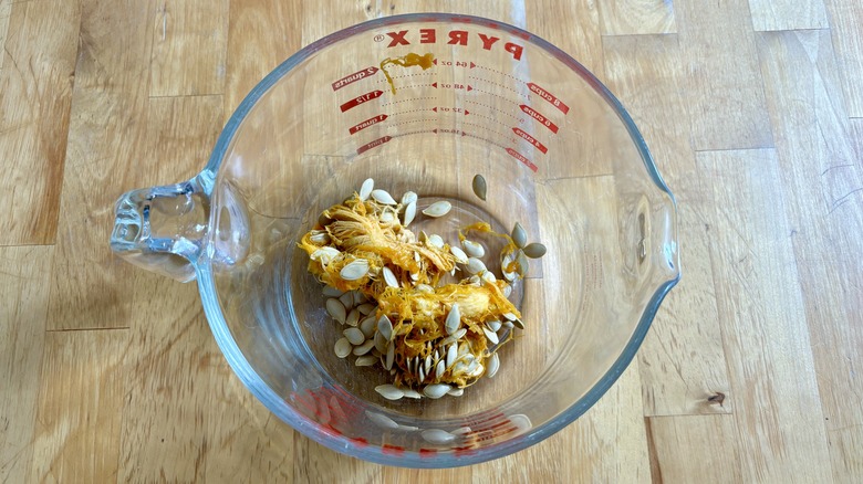 Pumpkin seeds and pulp in glass measuring cup