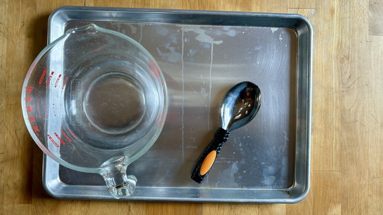 Baking sheet, measuring cup, and pumpkin scooper on wooden counter