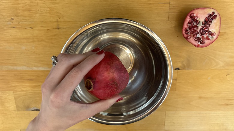 half pomegranate held over bowl