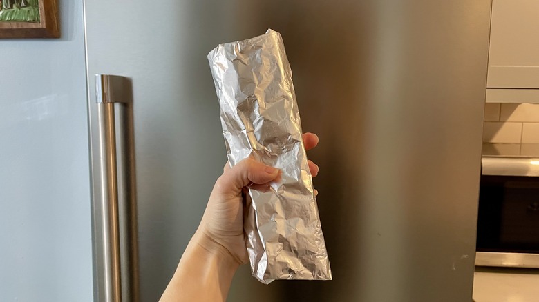 Hand holding foil-wrapped burrito