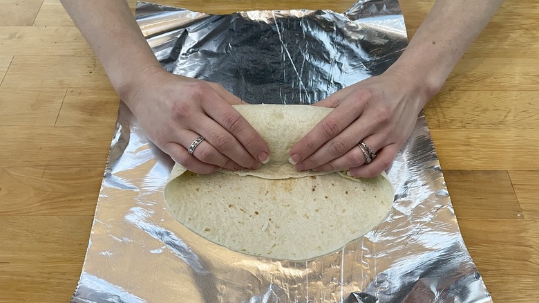Person tucking filling into tortilla