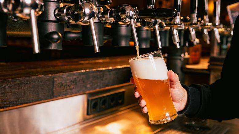 Bartender pouring draft beer with a thick foam head