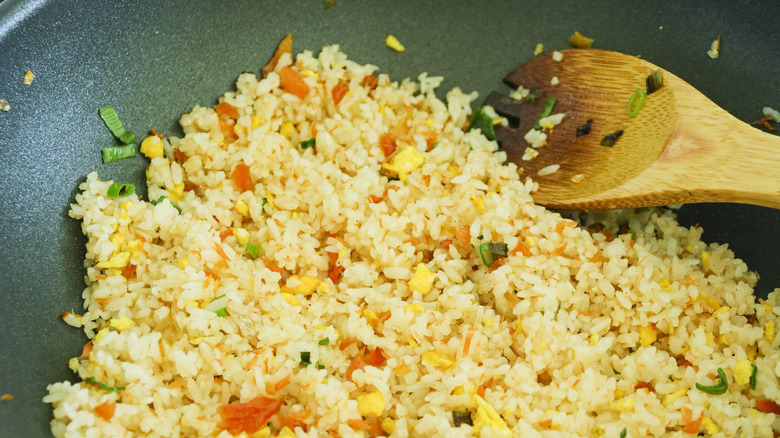 fried rice in a wok with a wooden spoon