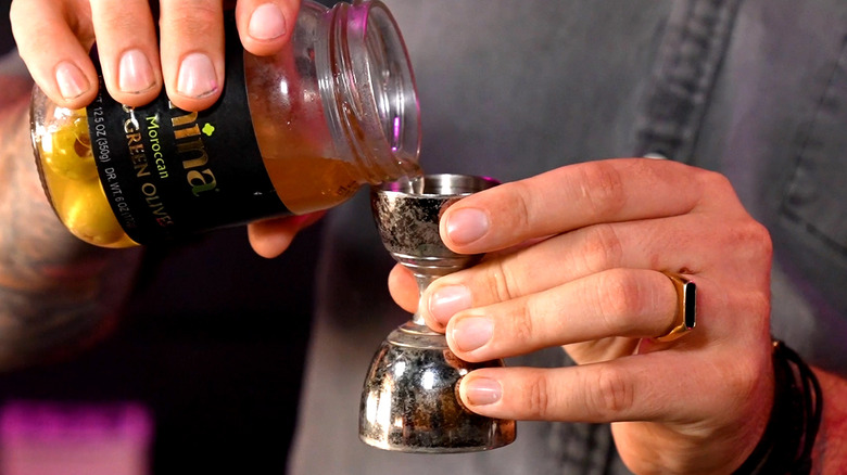 Pouring olive brine for martini