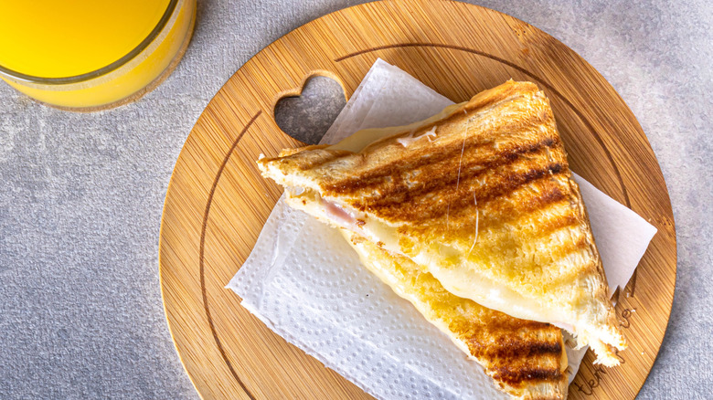 grilled ham and cheese sandwich on wooden board with napkin