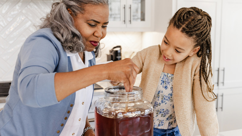 A woman and a child mixing a big jar of iced tea