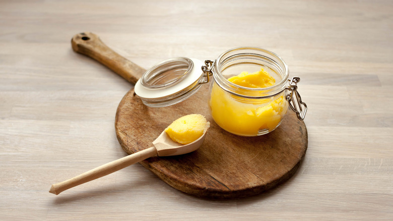 Jar of ghee on wooden board