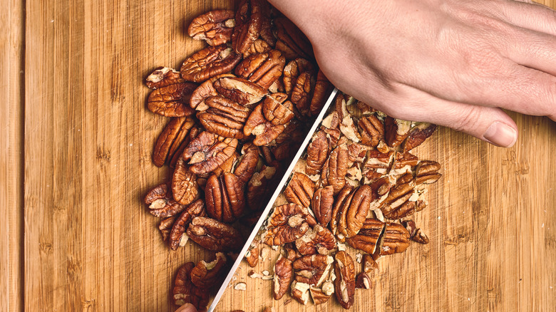 Hand with knife chopping pecans