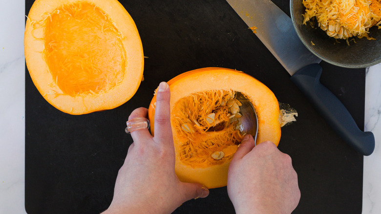 Hand removing seeds from pumpkin