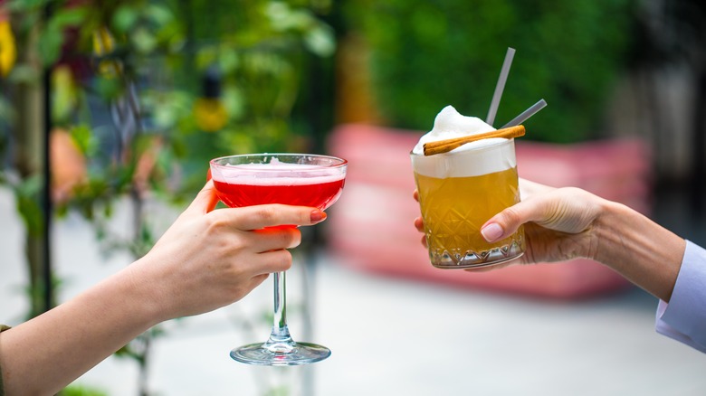 hands holding two cocktails