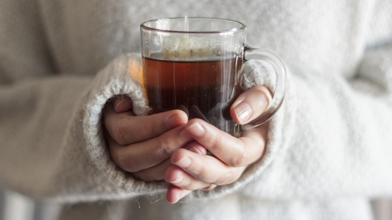 woman wearing sweater and holding hot cup of tea