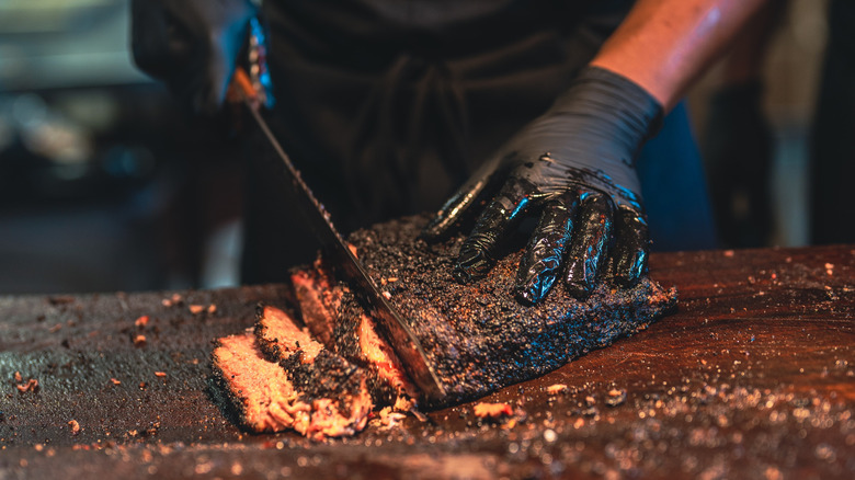 A barbecue chef slices a smoked brisket
