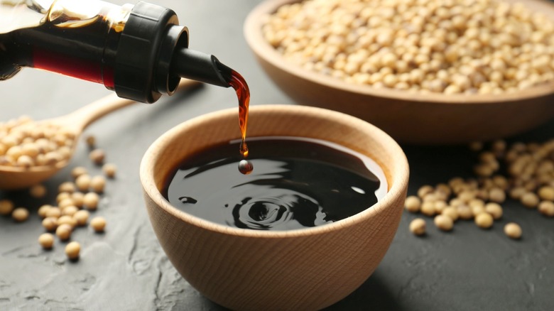 Bottle pouring dark brown sauce into cup