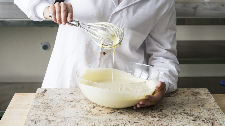 chef stirring melted almond bark with a whisk