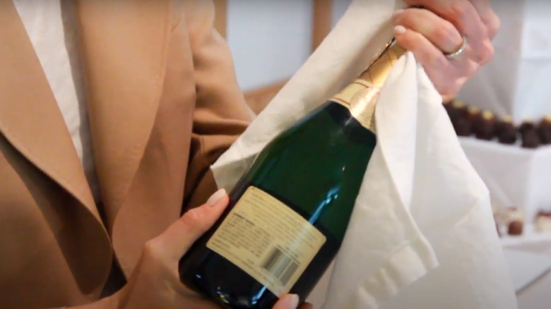 A linen towel over the cork of a Champagne bottle