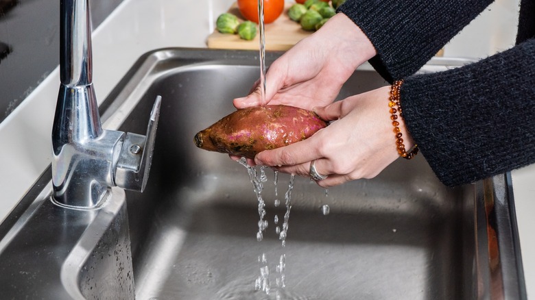 Person rinsing sweet potato