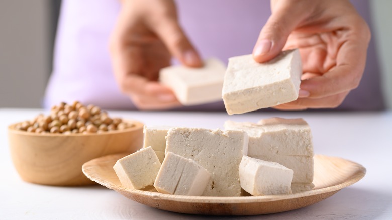 Person holding tofu next to plate of tofu