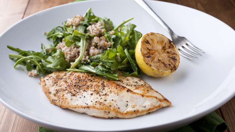 Chicken paillard with salad and a roasted lemon on a plate