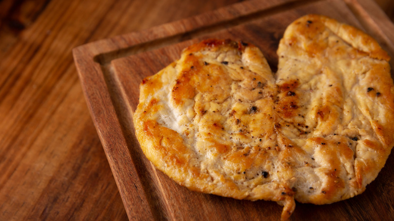 Butterflied, cooked chicken breast on a cutting board