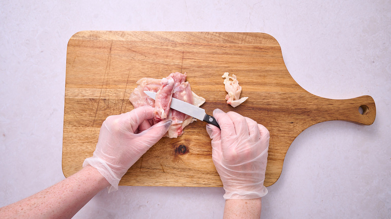 Slicing chicken bone away from the thigh