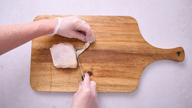 Trimming the fat from a chicken thigh