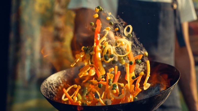 cook tossing stir-fry in a wok