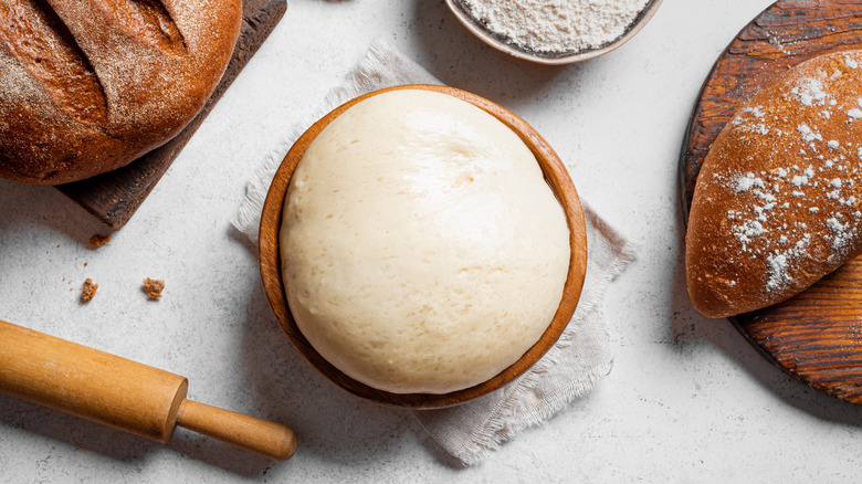 Bowl of fresh yeast surrounded by bread loaves