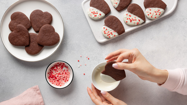 person dipping heart-shaped cookies into white sauce