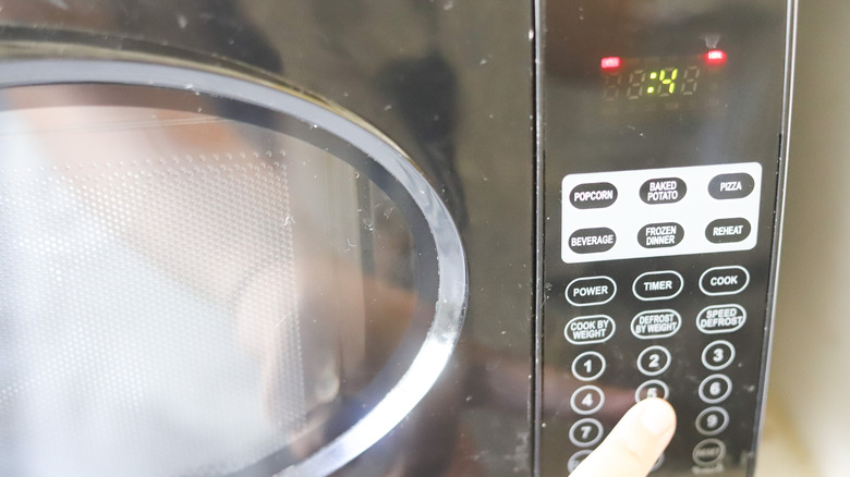 Hand touching microwave button