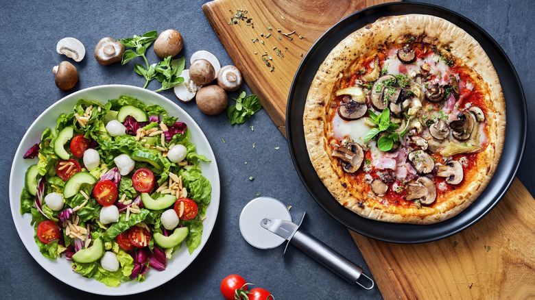 A bowl of salad and a pizza on plates